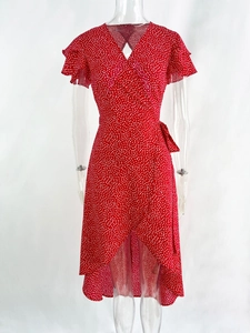 Detail of red polka dot wrap dress featuring ruffle sleeves and ruffled asymmetrical hemline
