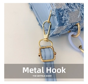 Détail du sac en jean bleu clair avec bords effilochés et crochet en métal doré