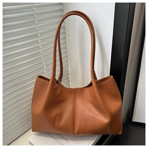 Detailed texture of brown faux leather tote bag with vertical center stitching and soft folds
