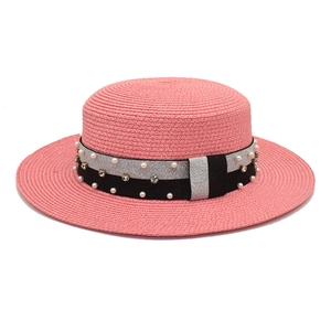 Detail of pink straw boater hat with wide brim and elegant pearl rhinestone ribbon trim