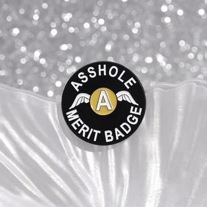 Pin's émaillé rigolo Asshole Merit Badge avec ailes et lettre A sur fond de coquillage