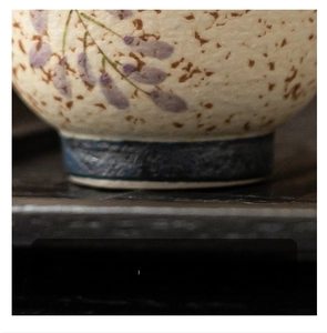 Detailed close-up of the smooth ceramic cup base with hand-painted wisteria patterns