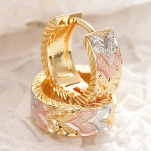Detail van gouden U-vormige oorbellen met roze en zilveren hartreliëfs en gravering