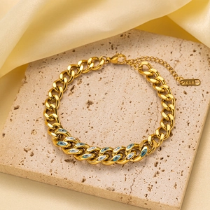 Detalle de pulsera de cadena cubana dorada con dijes de ojo turco azul y cierre K18
