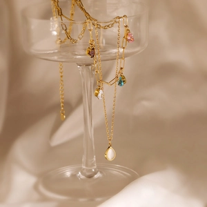 Detailed view of multilayer gold necklace with colorful teardrop zircon pendants on a glass