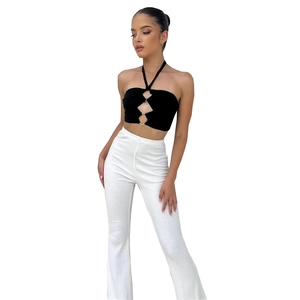 Detail shot of black halter top metal ring and white ribbed high-waisted flare trousers