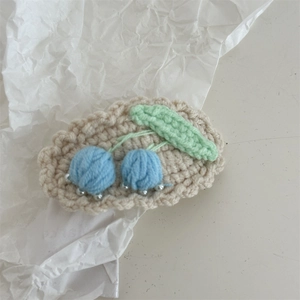 Close-up of handmade crochet hair clip featuring blue cherries and green leaf details