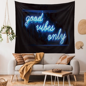 Detail of Good Vibes Only black tapestry with blue neon lettering above a sofa