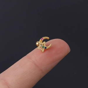 Macro view of tiny gold celestial moon and star cartilage stud with colorful zircon stones