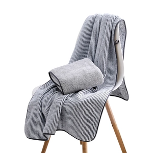 Absorbent bamboo charcoal fiber bath towel with gray stripes hanging on a white chair