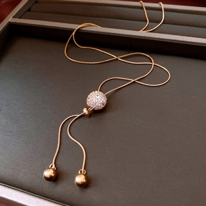 Detail of rose gold lariat necklace featuring a pave crystal ball and adjustable tassels