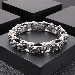 Detail of silver stainless steel skull bike chain bracelet on black geometric display