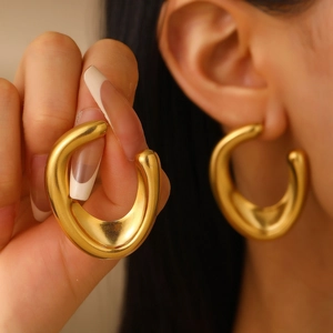 Detail of chunky gold irregular geometric earring with textured metal on ear