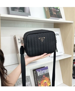 Close-up of black woven camera bag featuring a triangle metal logo and wide strap
