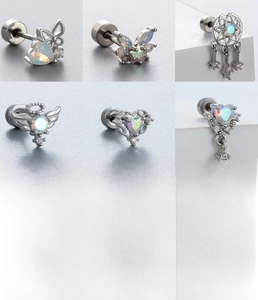 Détails macro des clous d'oreilles papillon et cœur en acier titane avec zircons