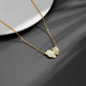 Elegant gold butterfly necklace with diamond inlay on a minimalist grey fabric background