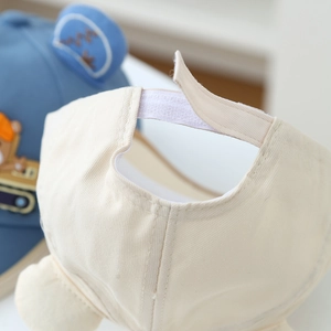 Detail of adjustable velcro strap on cream cotton baseball cap with bear embroidery