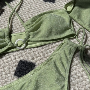 Detail of sage green bikini set with shimmering metallic finish and ring hardware