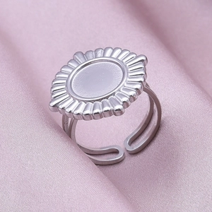 Macro detail of adjustable stainless steel gear ring with smooth center on pink silk