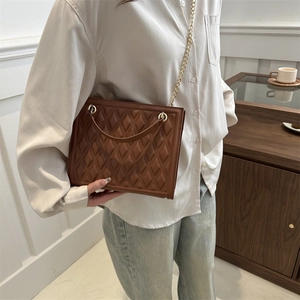 Quilted brown leather crossbody bag with gold chain strap shown in an elegant interior