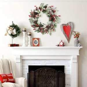 Close-up of Christmas wreath with red berries, pine cones and needles on white fireplace