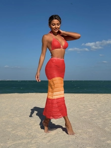 Dettaglio del top bikini rosso e gonna lunga in maglia a righe sulla spiaggia