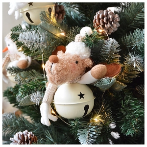 Close-up of plush reindeer ornament with cream metal star bell hanging on Christmas tree