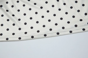 Macro detail of white polka dot fabric with precise double-needle stitching and smooth hem