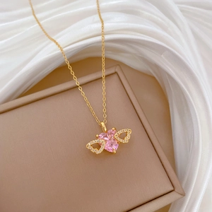 Detail of gold heart pendant with crystal wings on white silk and beige jewelry box