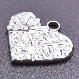Détail du pendentif en cœur argenté avec relief floral et texture martelée élégante