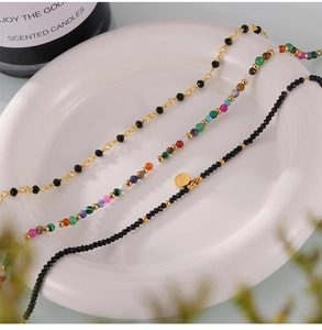 Detailed shot of handmade anklets with natural stones and 18k gold smiley pendants