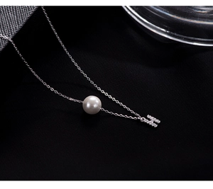Macro detail of S925 silver necklace with white pearl and sparkling H letter pendant