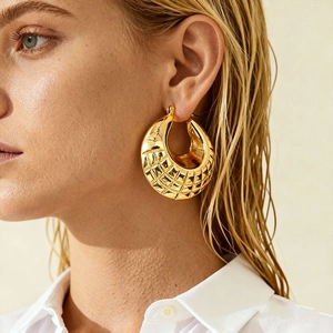 Detailed close-up of a gold geometric earring with diamond lattice pattern on a model