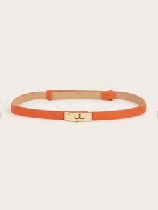 Macro detail of orange Saffiano leather belt with golden metal twist lock buckle