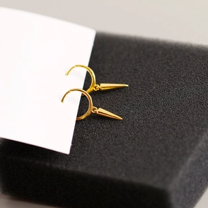 Macro shot of gold hoop earrings with cone pendant on a high contrast background