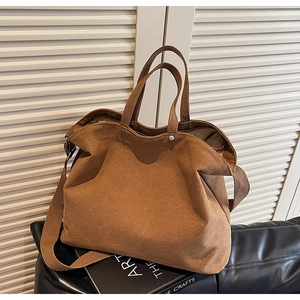 Brown canvas tote bag with reinforced handles and metal buckles on a premium leather mat