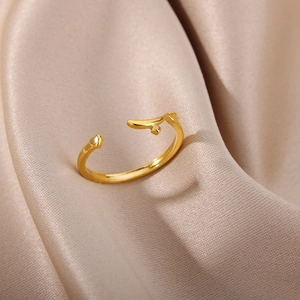 Macro shot of rose gold open ring with heart and branch detail on champagne silk fabric