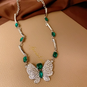 Detailed view of silver butterfly necklace with green gems and rhinestones on leather