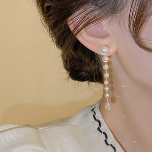 Détail de longues boucles d'oreilles en perles avec cristal sur un mannequin femme