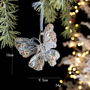 Golden glitter butterfly Christmas tree ornament hanging on a festive green branch