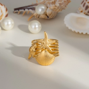 Détail d'une bague dorée style marin avec charmes d'étoile de mer et de coquillages