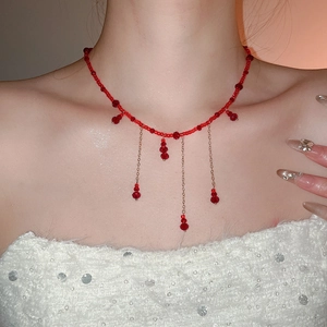 Detailed view of red crystal beaded necklace with golden chain tassels and waterdrop charms