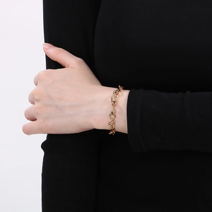 Detail shot of a golden infinity link chain bracelet on wrist with polished metallic texture