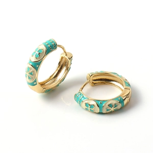 Macro detail of gold enamel hoop earrings with turquoise and white clover pattern