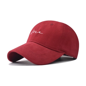 Detailed view of white 'me' script embroidery on burgundy cotton canvas baseball cap