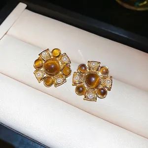 Vintage gold stud earrings with brown gemstone and pearls on a beige jewelry display