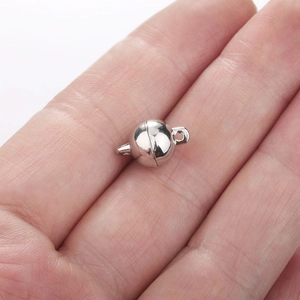 Close-up of a silver spherical magnetic clasp on a hand for DIY jewelry making
