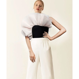 Detail des schwarzen Schlauch-Tops mit dramatischen weißen Tüllrüschen und weiter Hose