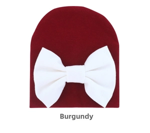 Detail of infant wine red knitted beanie with a large white bow for newborn babies