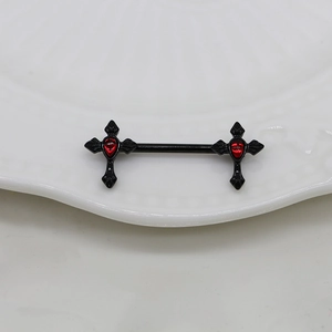 Macro detail of black barbell nipple ring with red gem-set gothic cross on ceramic